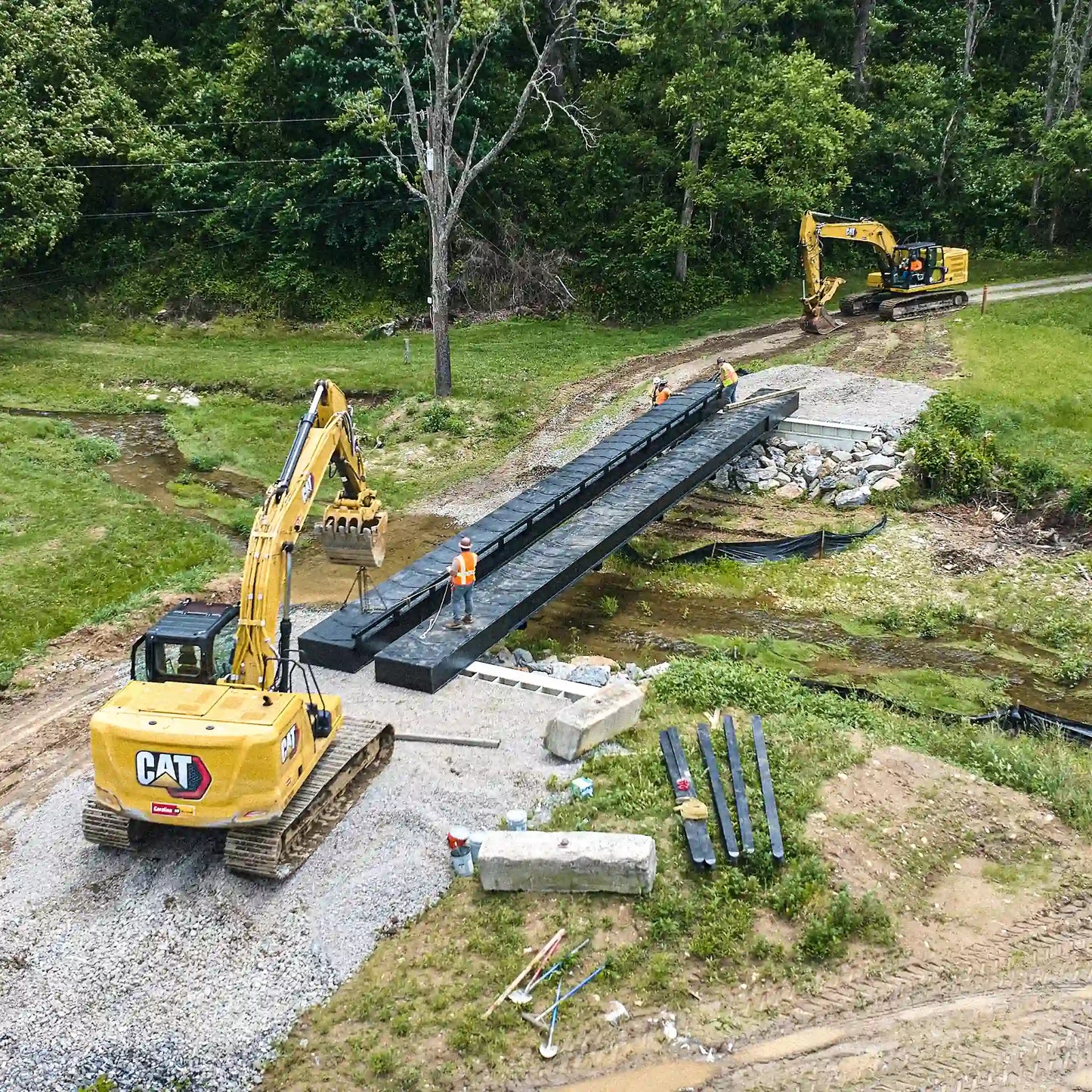 Aerial view of modular steel bridge installation at a rural creek crossing