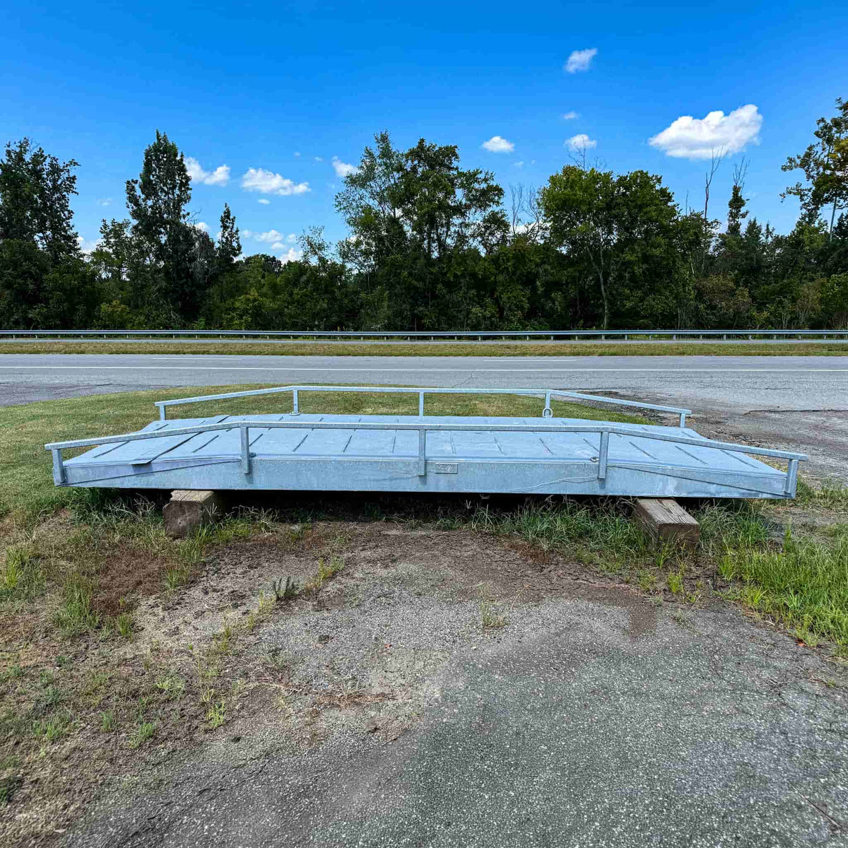 Used 20-foot steel ATV bridge with side rails on wood cribbing, side view