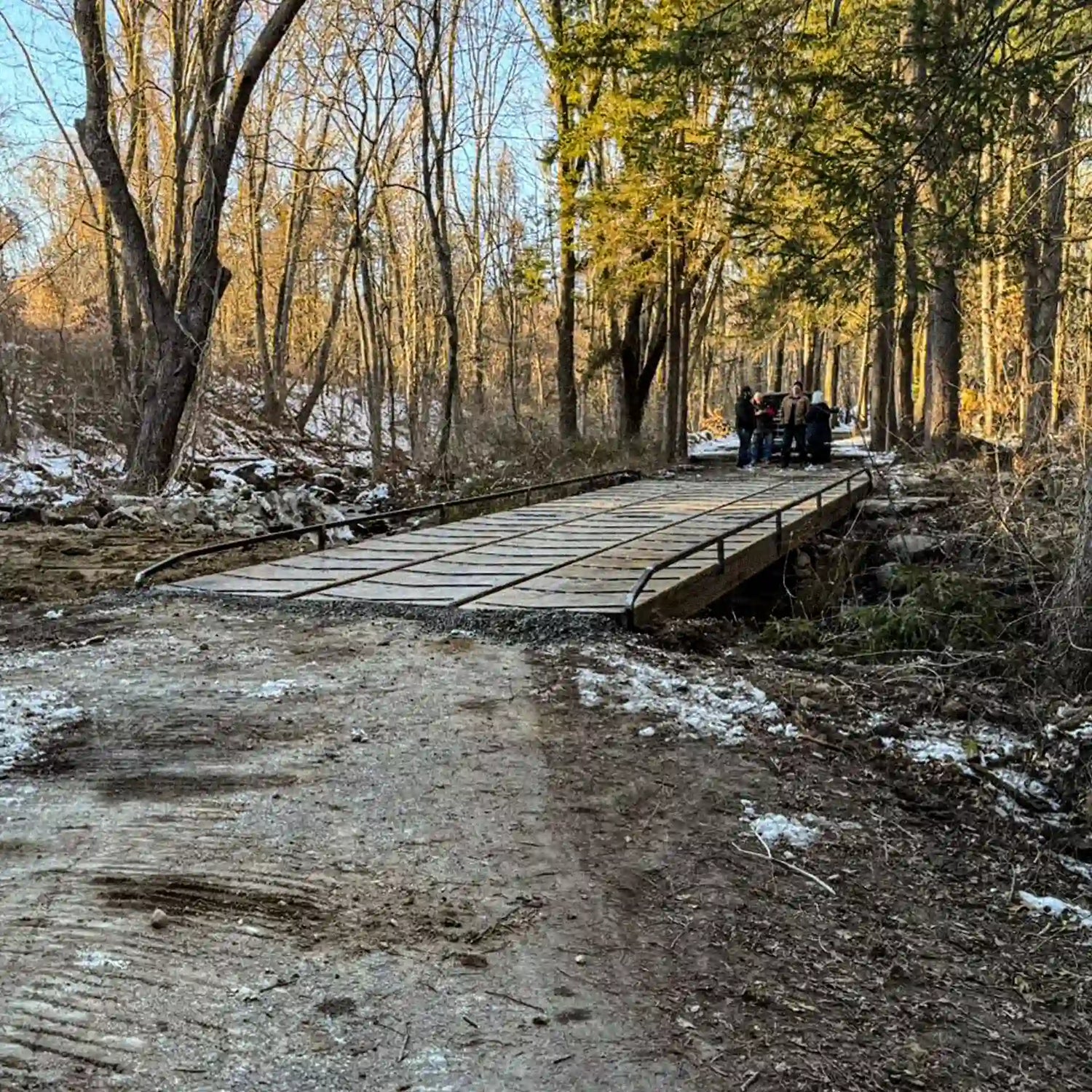 Long steel construction bridge installed across a work zone, with gravel approaches and construction equipment in the background.