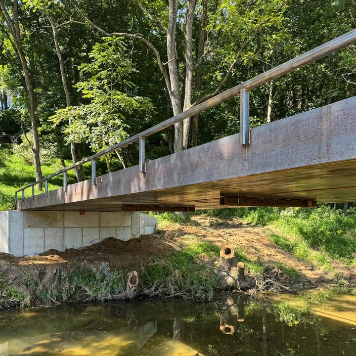 portable steel bridge over a stream in a wooded area