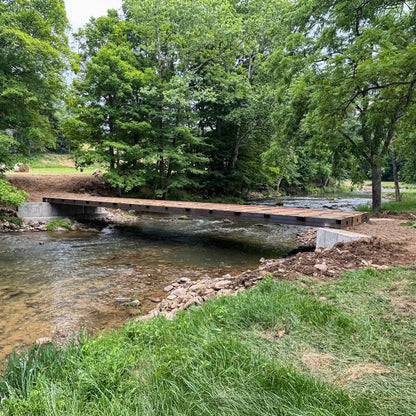 portable steel bridge over a stream in a wooded area