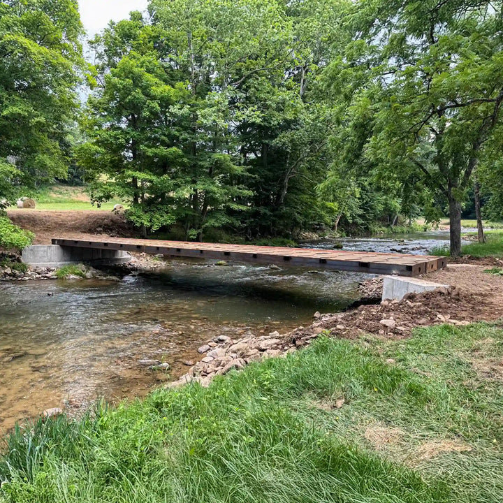 portable steel bridge over a stream in a wooded area