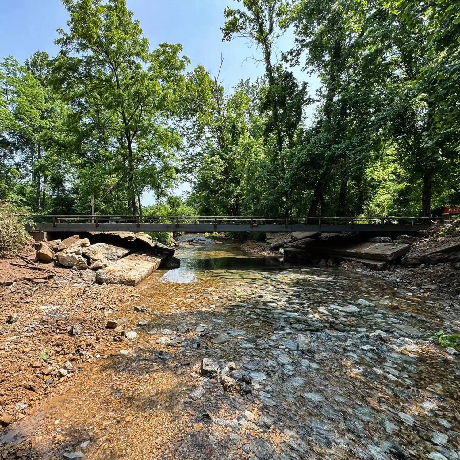 portable steel bridge over a stream in a wooded area