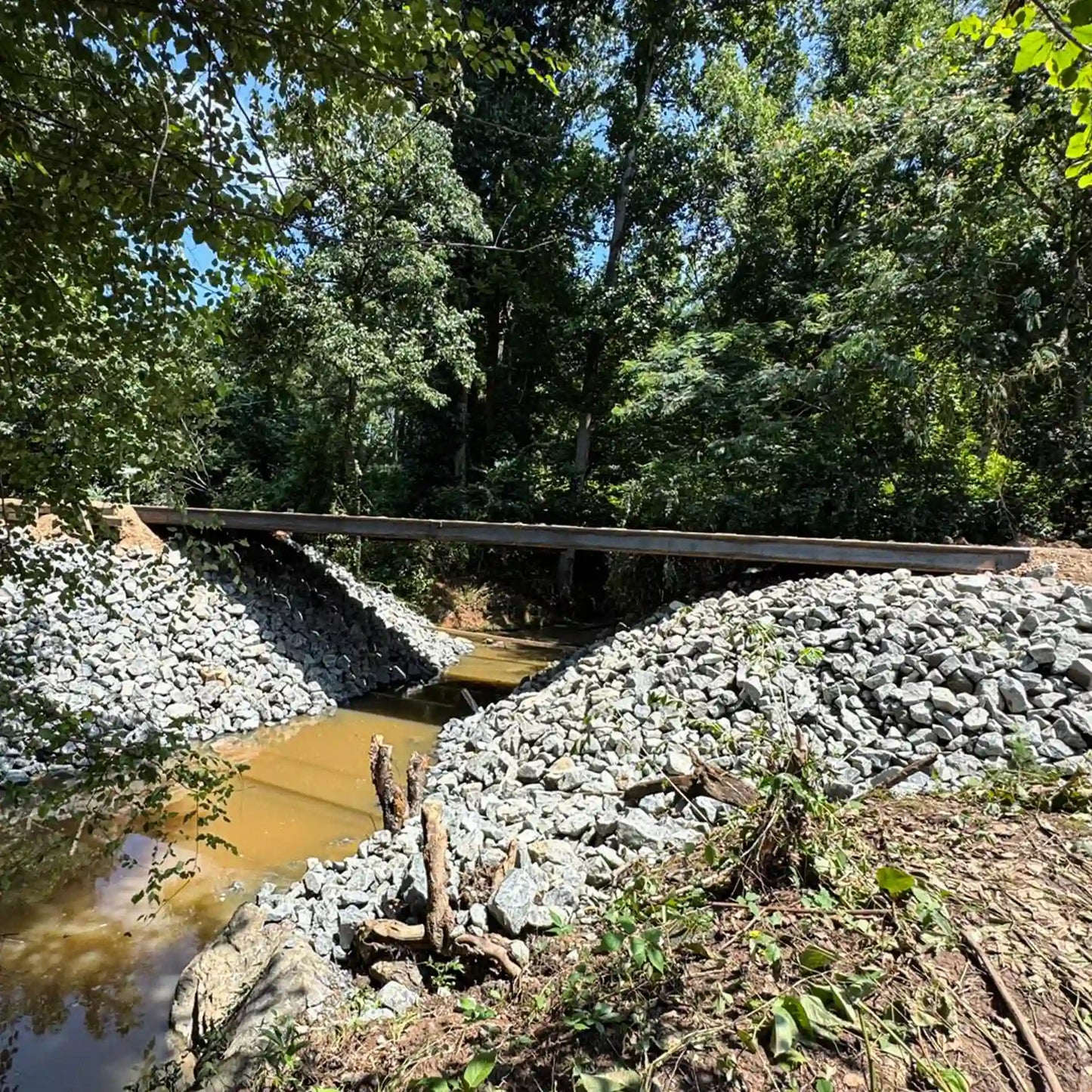 portable steel bridge over a stream in a wooded area