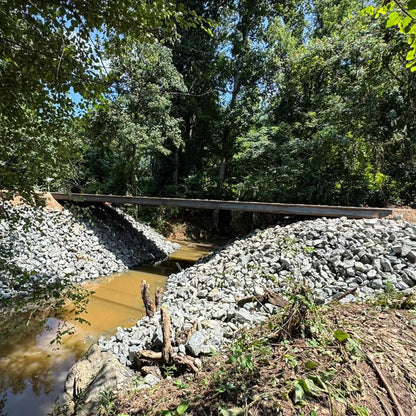 portable steel bridge over a stream in a wooded area