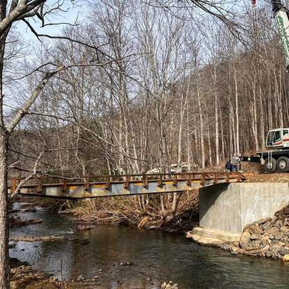 Construction site with a rail car bridge over a stream in a forested area