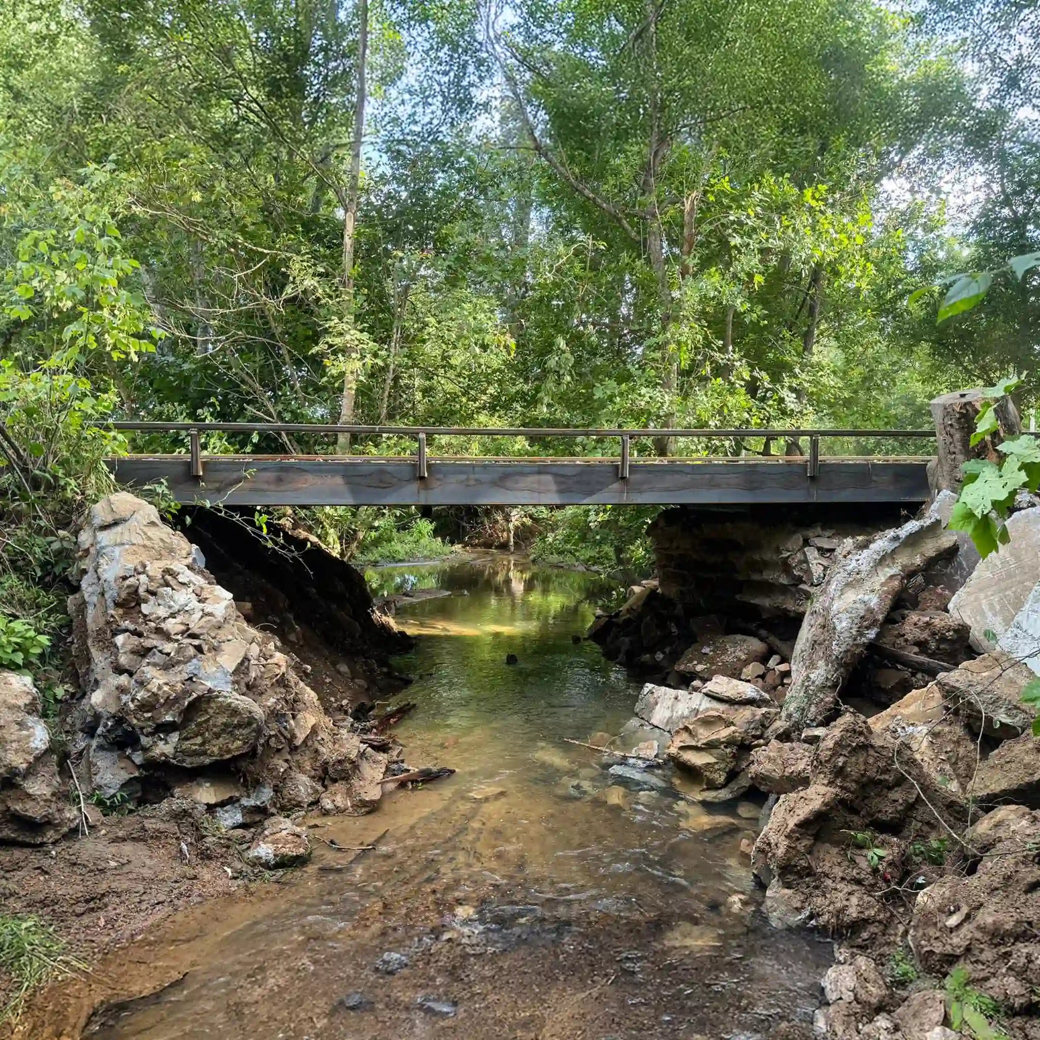 portable steel bridge over a stream in a wooded area