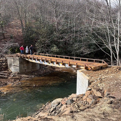 a rail car bridge over a stream in a wooded area