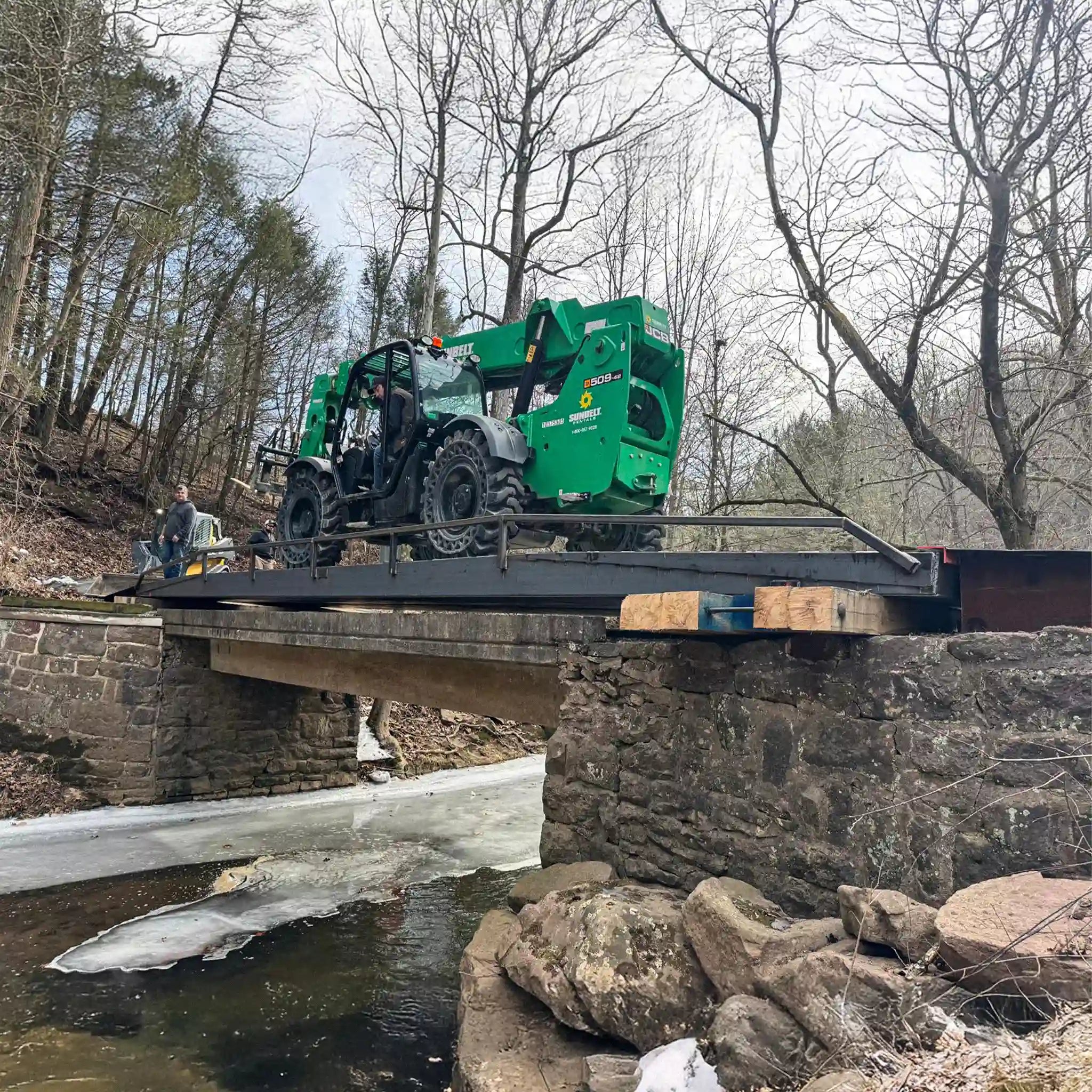 A portable steel bridge over a stream in a wooded area