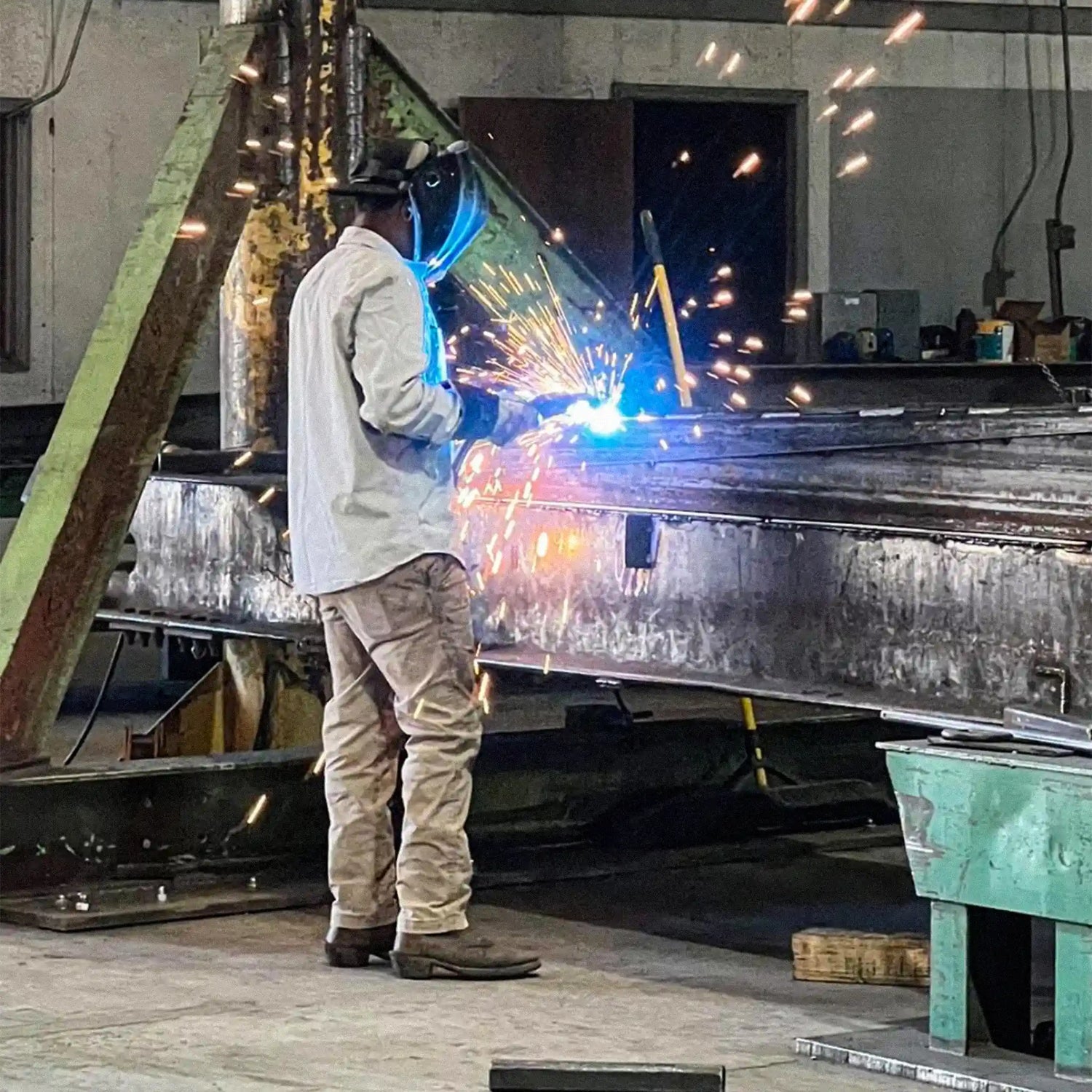 a man welding a portable steel bridge in an industrial warehouse