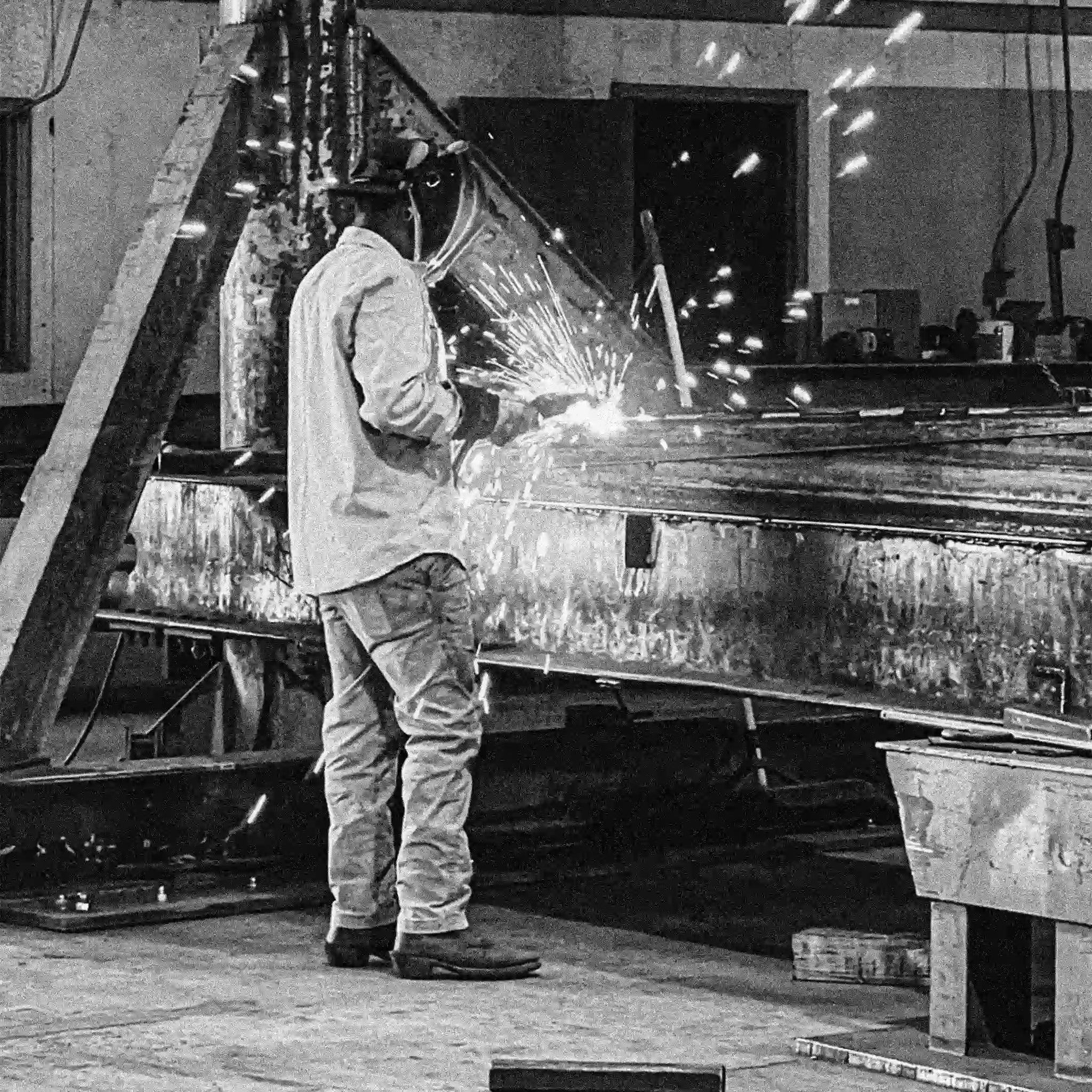 person welding a portable steel bridge in a warehouse