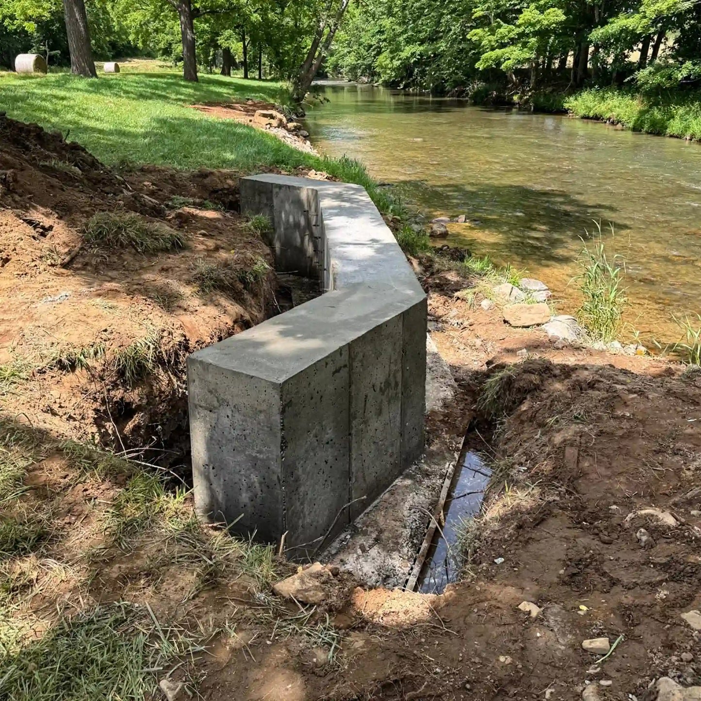 poured cement bridge foundation at a construction site next to a stream in a wooded area