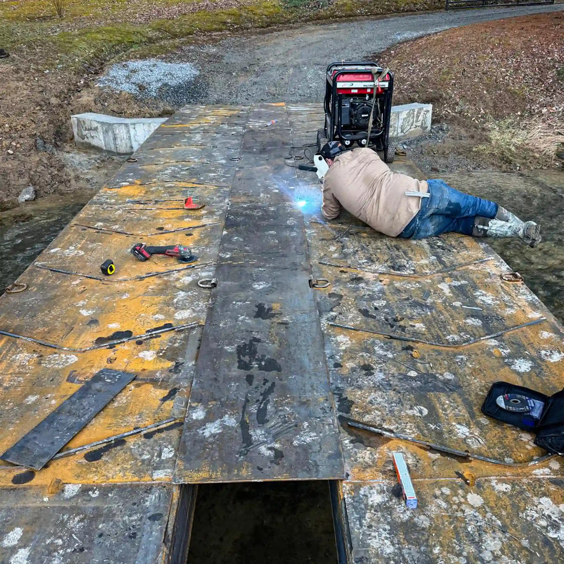 man welding a portable steel bridge outdoors