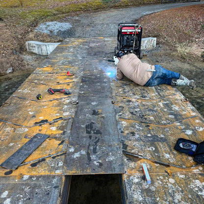 man welding a portable steel bridge outdoors