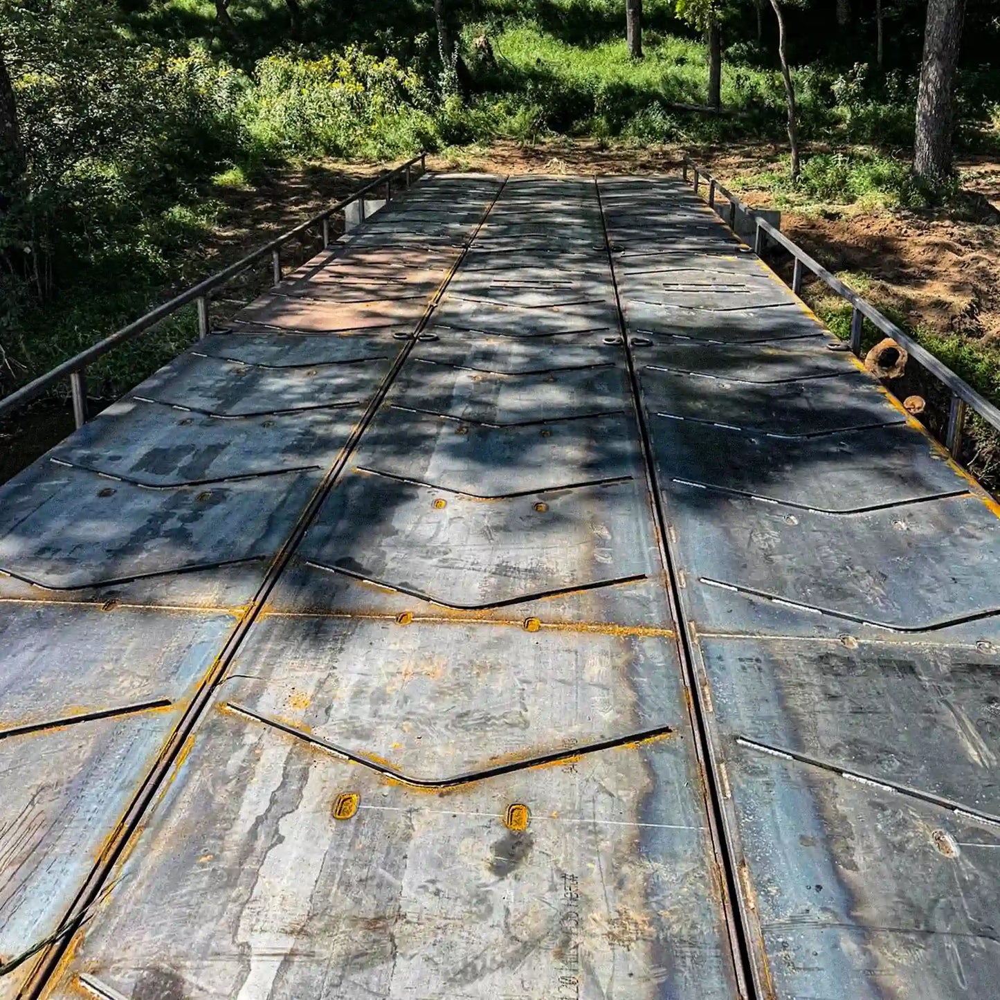 Close-up view of the steel deck surface on a modular residential bridge, showing textured steel panels and side rails.