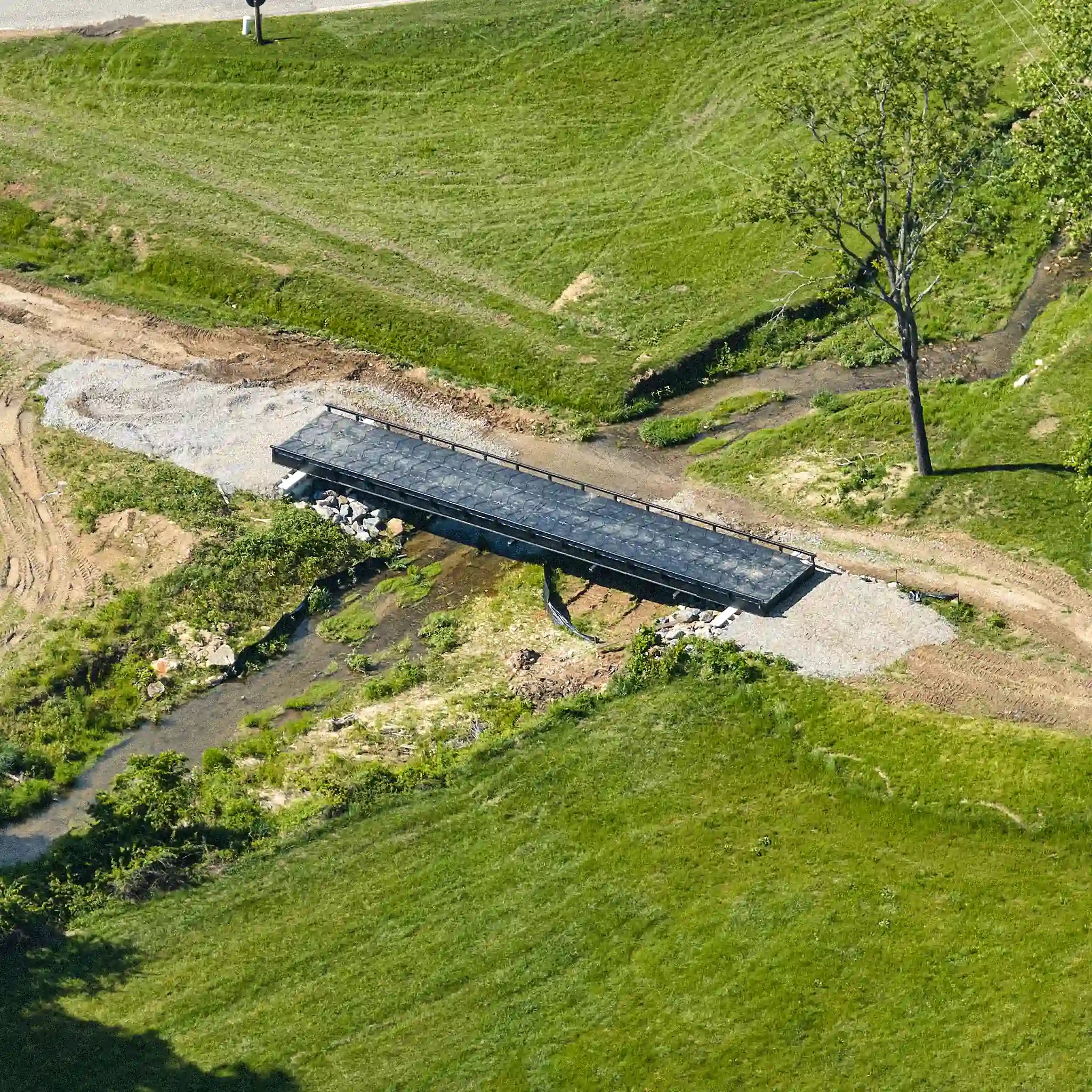 Aerial view of a modular steel bridge spanning a creek on a rural property