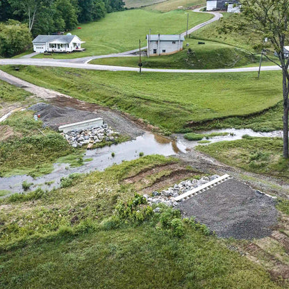 Aerial view of creek crossing prepared for modular steel bridge installation