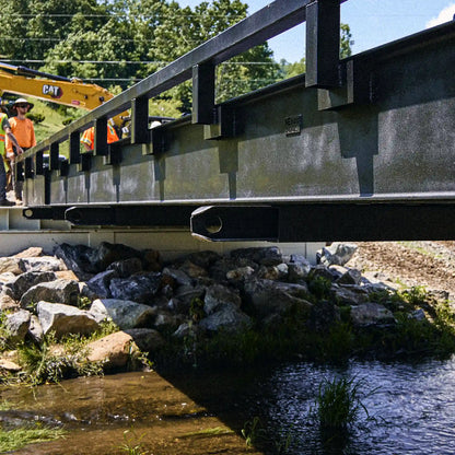 Finished modular steel bridge with railings installed over a creek