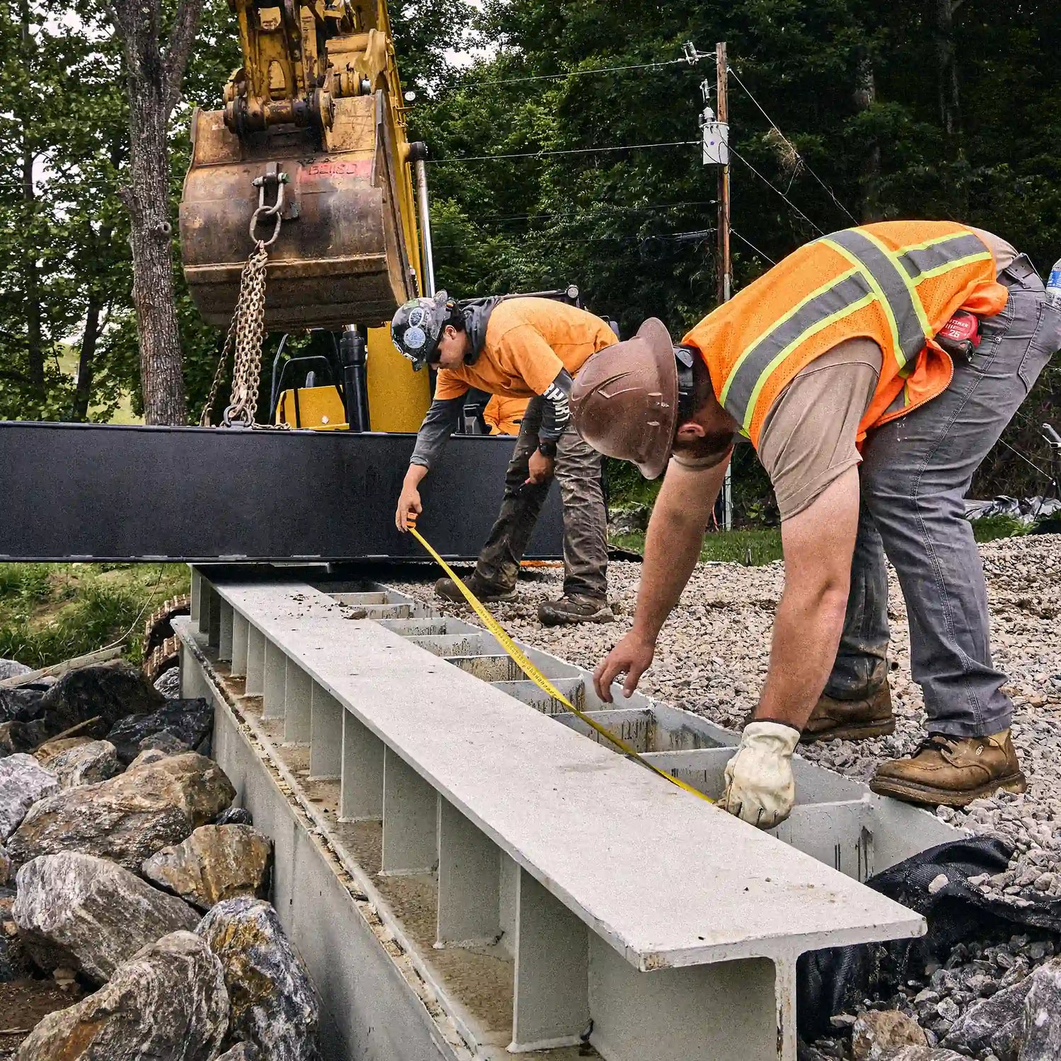 Installers measuring a concrete bridge abutment before setting the steel bridge