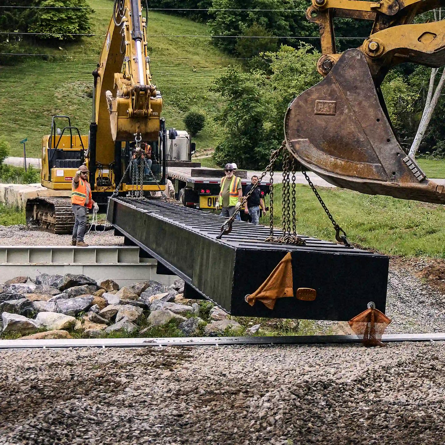 Modular steel bridge section being lowered onto a creek crossing abutment