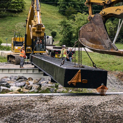 Modular steel bridge section being lowered onto a creek crossing abutment