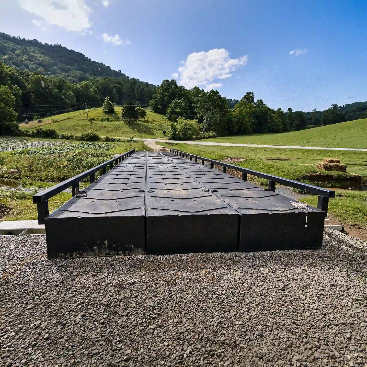 View across a modular steel bridge deck with railings in rural farmland