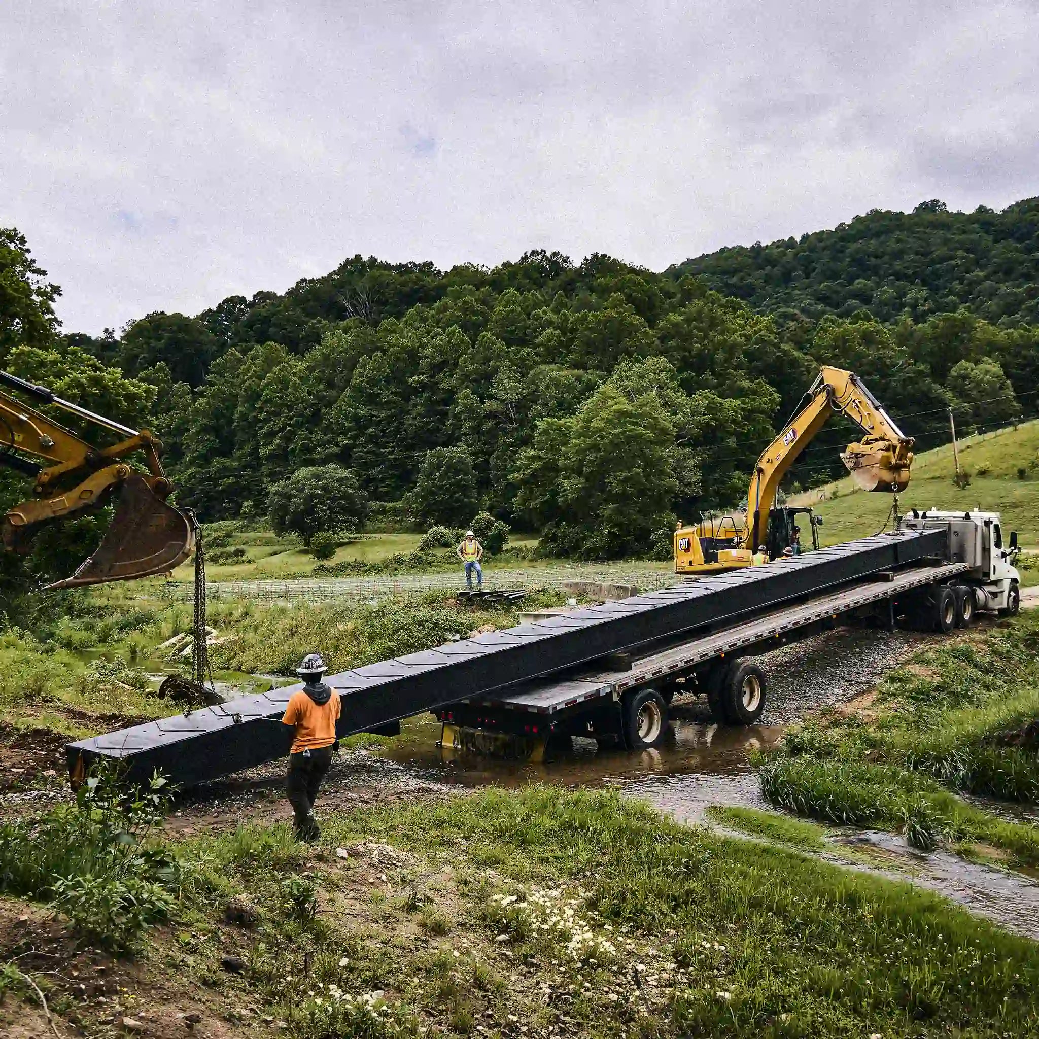 Rural modular steel bridge installation using excavators and a flatbed truck